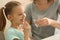 Young mother giving pill to her daughter, indoors