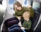 Young mother helping her little son with safety belt during traveling by an airplane