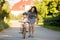 Young mother, helping her son to learn how to ride a bike, holding him and teaching him