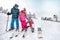 Young mother helps to daughter to properly puts ski shoes on ski