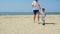 A young mother and her child are playing a ball on a sandy beach. Happy family are playing football. The concept of