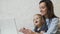 Young mother with her child working on laptop at home.