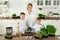 Young mother and her children pose in the kitchen at the table during the microgreen planting. Healthy food, citiferma.