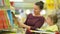 Young mother with her daughter choose books in supermarket. Beautiful daughter sitting in a supermarket cart and