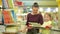 Young mother with her daughter choose books in supermarket. Beautiful daughter sitting in a supermarket cart and