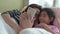 Young mother and her daughter girl are playing mobile phone in bedroom.