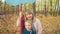 A young mother and her a little adorable daughter with the colorful balloons are walking in autumn forest.