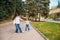 A young mother and her little daughter are dancing in the park. A girl and a woman are circling on the sidewalk