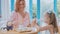 Young mother and her little daughter spending time in a cafe with ice cream