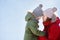 Young mother and her little son embrace and having fun together during stroll in snowy winter park