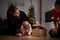 Young mother and her two daughters sitting on living room floor peeking inside a slightly open gift box