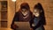 A young mother in a hijab sits with her little daughter on the couch in the evening and uses a tablet, watch a strange