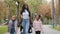 Young mother hold two daughters by hands happy friendly African American family walking in city park on weekend little