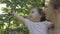 Young mother holding a baby girl on hands while baby eating cherries straight from the tree