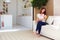 Young mother holding on hands infant baby, while sitting on open space kitchen