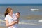 Young mother holding her newborn daughter on beach