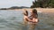 young mother holds in arms little daughter in shallow sea water