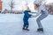 A young mother holds the hand of a little boy 2-4 years old child. In winter, on rink in city. Happy relaxing in the