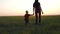 A young mother holds her daughter`s hand. Happy family walking in the fresh air at sunset.