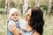 A young mother holds the little daughter of the infante in the park in the summer