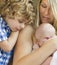 Young Mother Holds Newborn Baby Girl as Brother Looks On