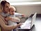 Young mother in home office with computer and her baby. Freelancer or blogger, work and child care.