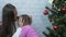 Young mother hugging her crying little daughter next to Christmas tree