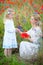 young mother and kid girl in white dresses on summer meadow. Daughter gathered wild flowers for mom