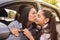 Young mother kissing her daughter on the cheek before entering school from the car