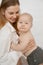 Young mother with little baby laugh and smile on white background. Portrait of happy woman and naked infant child