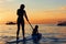 Young mother with little clild paddling on stand up paddleboard