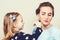 Young mother and little daughter while applying makeup. Beauty and fashion. Mom and child girl celebrate mother`s day. Cute littl