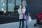 Young mother with little daughter on the arms. Father with shopping bags in hand. Family shopping. Mall on background