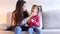 Young mother with little daughter sitting on couch in living room.