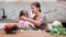 Young mother and little daughter smiling cooking vitamin salad adding cucumber. Shot with RED camera in 4K