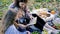 young mother and little daughters on a picnic outdoors reading a book together