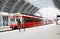 Young mother and little kid walk through the Bergen train station platforms with typical red Voss train on background, Bergen.