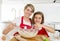 Young mother and little sweet daughter in cook apron cooking together baking at modern home kitchen