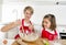 Young mother and little sweet daughter in cook apron cooking together baking at modern home kitchen