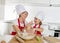 Young mother and little sweet daughter in cook hat and apron cooking together baking at home kitchen