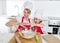 Young mother and little sweet daughter in cook hat and apron cooking together baking at home kitchen
