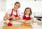 Young mother and little sweet daughter cooking in kitchen preparing desert with rolling pin rod