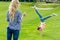 young mother looking at cute little daughter performing handstand on green grass