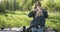 Young mother makes ponytails to her little daughter. Mom with child at picnic in park.