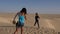 Young mother making photo on mobile phone to daughter on sandy desert background