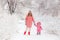 A young mother and one-year-old baby girl walk holding a pen in a winter park. photo shoot mother and daughter in pink winter