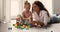 Young mother play multi colored wooden cubes with little daughter