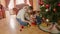 Young mother playing with baby boy under Christmas tree at living room