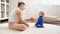 Young mother playing ball with her little baby son on soft carpet in living room. Family healthcare, active lifestyle, parenting