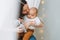 Young mother playing with cute baby boy in bright bedroom  natural tones  love emotion